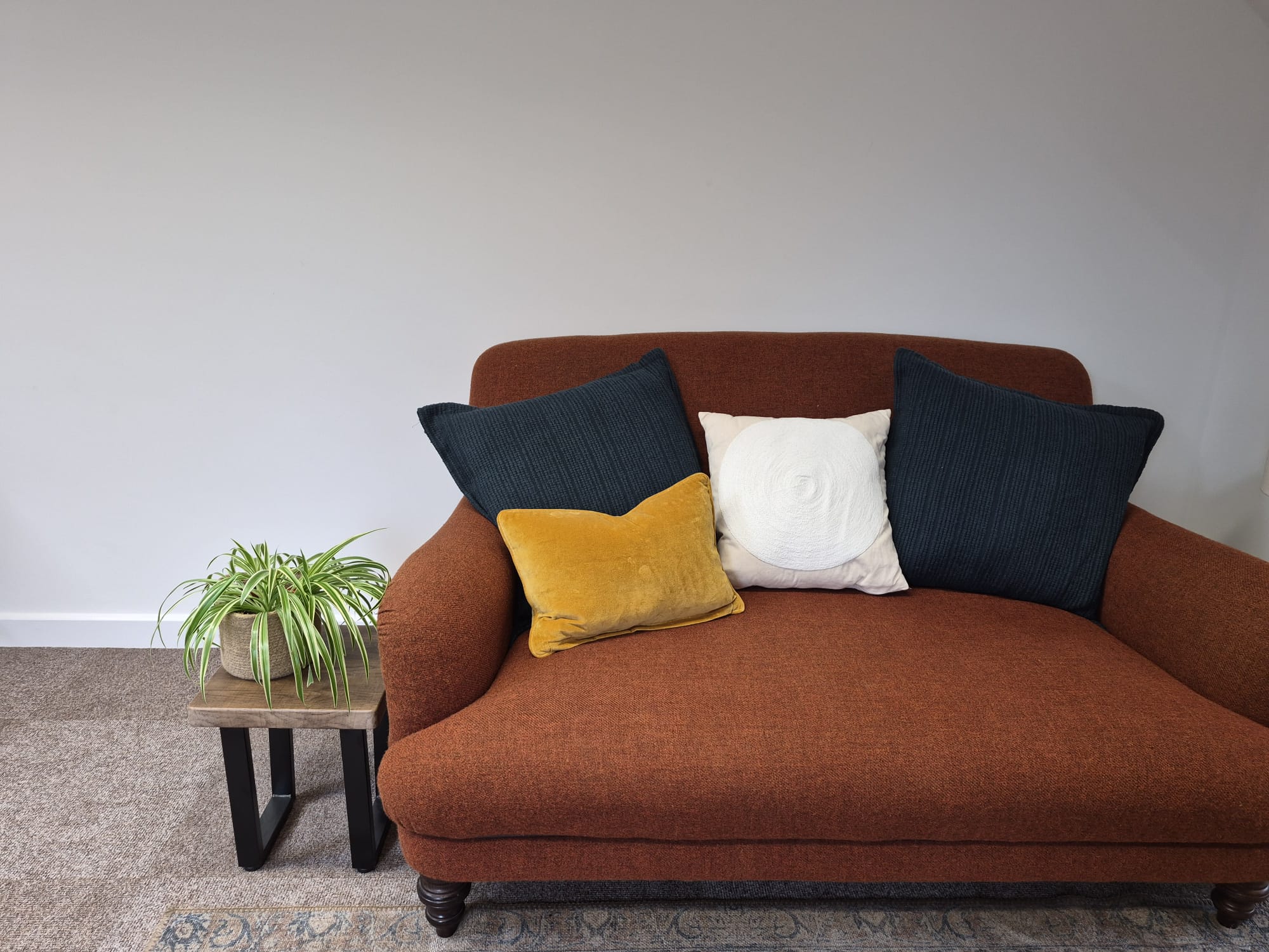 Make yourself comfortable Orange couch with cushions and a side table with plant